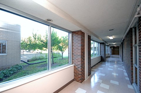 A long hallway with brick columns and a checkerboard floor.