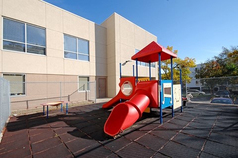 A red and blue playground slide in front of a building.