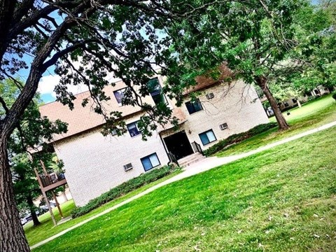 A house with a green lawn and trees in front.