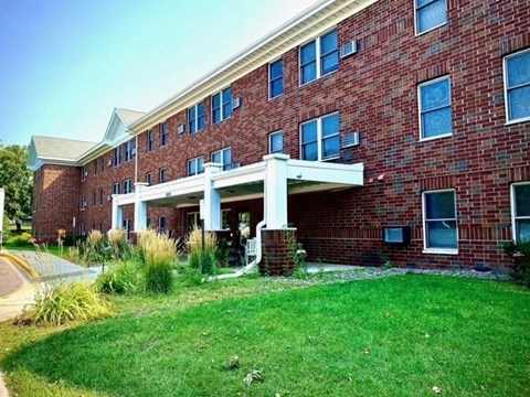 A red brick building with a white overhang and a green lawn in front.