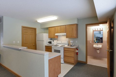 A kitchen with a white counter top and wooden cabinets.