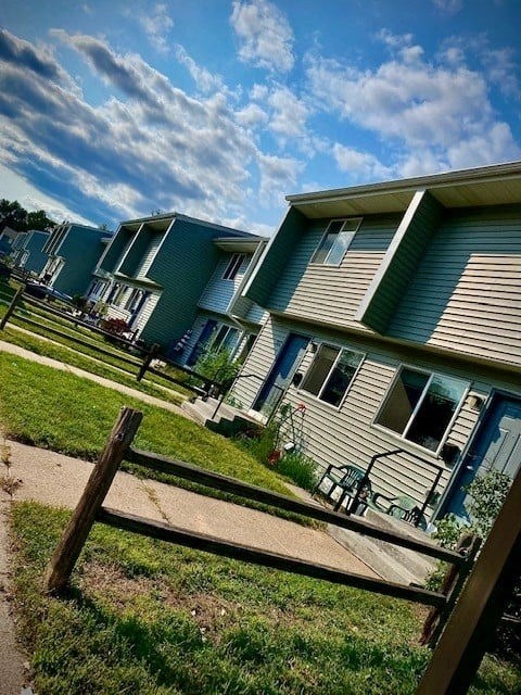 A row of houses with green siding and blue trim.