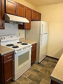 A kitchen with a white stove top oven and a white refrigerator.
