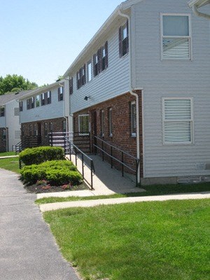 A white building with a brick entrance and a metal railing.