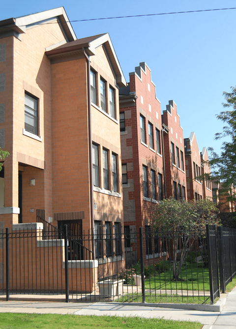 a row of brick apartment buildings with a black fence in front of them