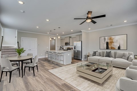A modern living room with a dining table and a kitchen in the background.