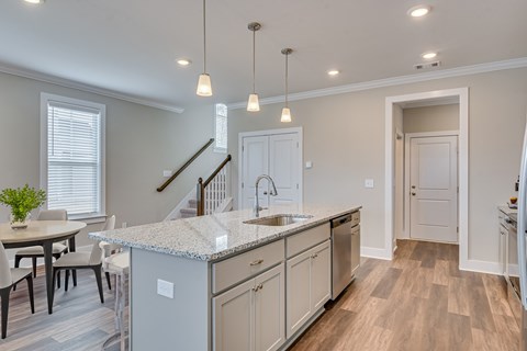 A kitchen with a marble countertop and a dining table with chairs.