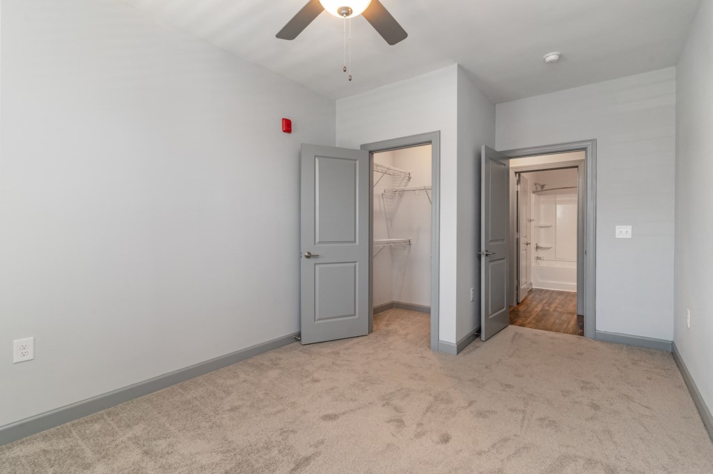 a bedroom with a ceiling fan and a closet with two doors at The Parker Myrtle Beach, Myrtle Beach