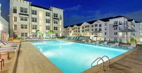 a swimming pool with lounge chairs and umbrellas next to a building at The Eddy at Riverview, Smyrna
