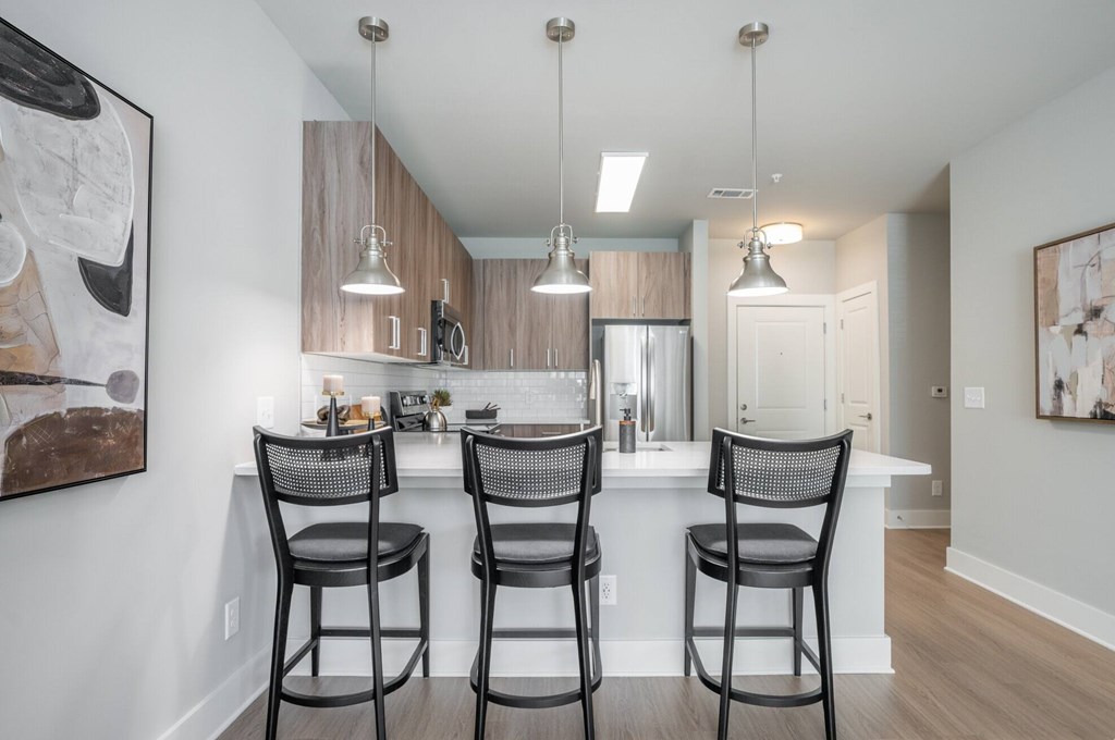 A kitchen with a bar area and chairs.at The Delaney at East Park Apartments, Kennesaw, GA