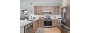 A modern kitchen with wooden cabinets and stainless steel appliances.at The Delaney at East Park Apartments, Kennesaw, GA, 30144