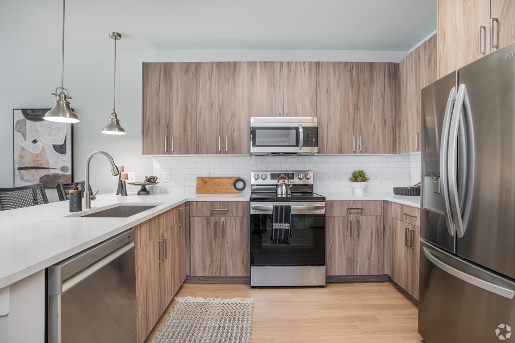A modern kitchen with wooden cabinets and stainless steel appliances.at The Delaney at East Park Apartments, Kennesaw