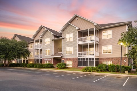 Apartment building with a parking lot in front.