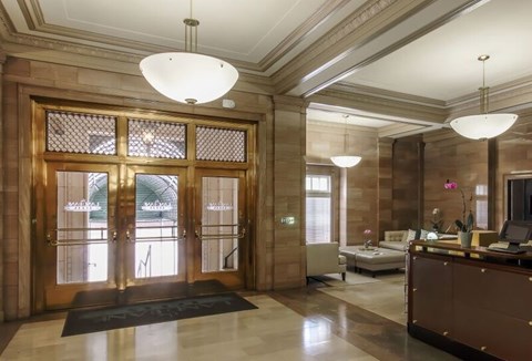 A reception area with a large glass door and a black carpet.