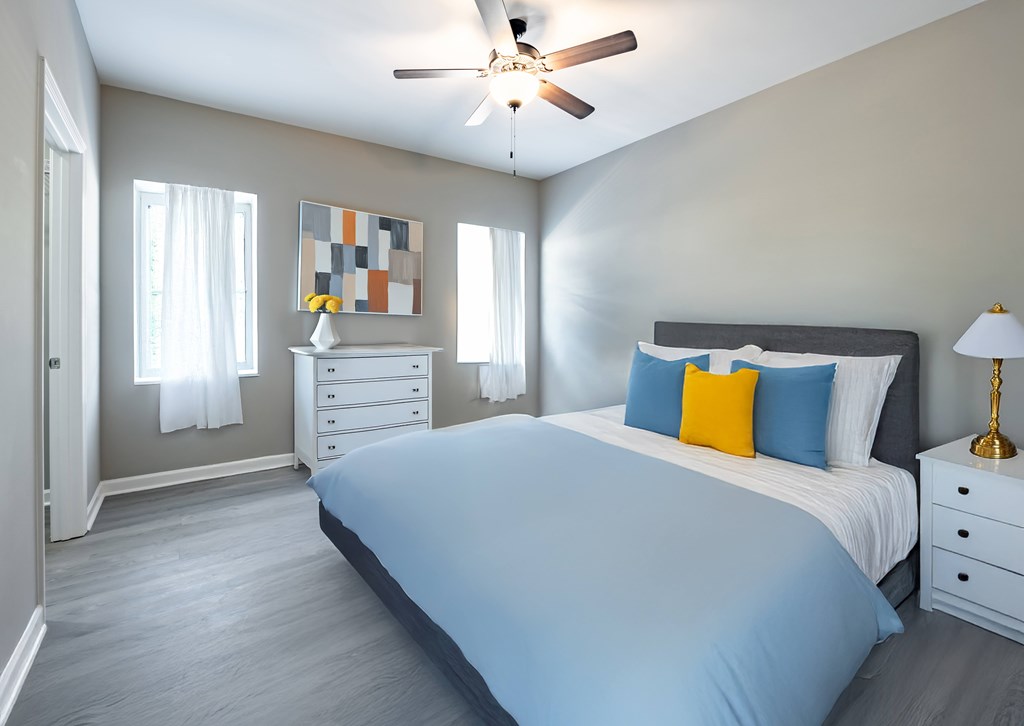 A bedroom with a bed, dresser, and ceiling fan at Club Villas Apartments, Kathleen, GA