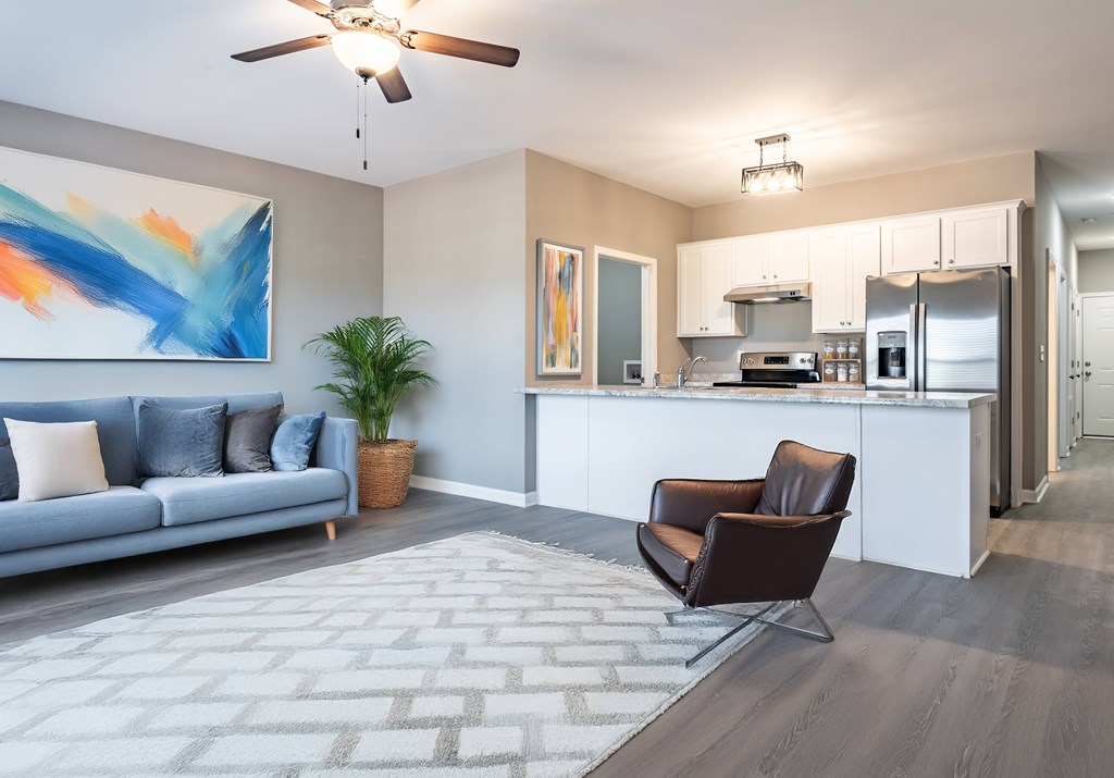 A modern living room with a grey sofa and a brown leather chair at Club Villas Apartments, Kathleen, Georgia
