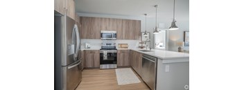 A modern kitchen with wooden cabinets and stainless steel appliances.at The Delaney at East Park Apartments, Kennesaw