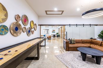 a living room with couches and a table with hats on the wall at The Parker Austin, Pflugerville, TX