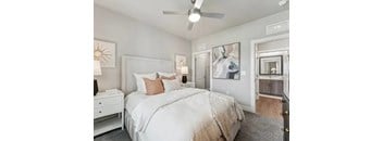 A bedroom with a large bed, a ceiling fan, and a dresser.