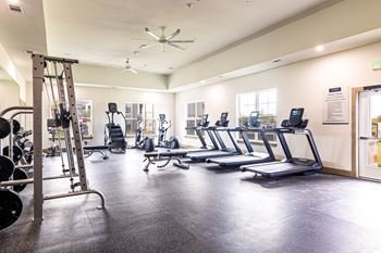 a gym with cardio equipment and weights on the floor at The Parker Austin, Pflugerville, Texas