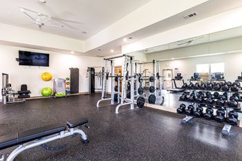 a gym with weights and mirrors on the floor and a wall mounted tv at The Parker Austin, Pflugerville