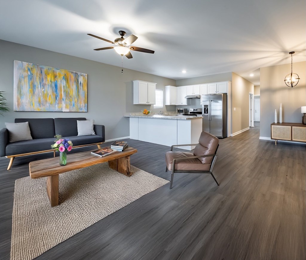 A modern living room with a grey sofa, a wooden coffee table, and a painting on the wall at Club Villas Apartments, Georgia, 31047