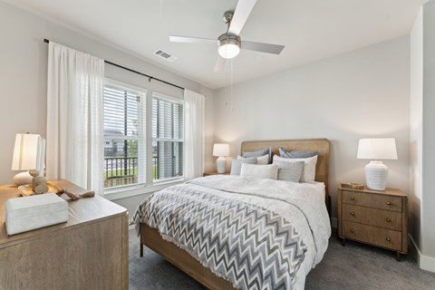 A bedroom with a large bed, a ceiling fan, and a window with blinds at The Hendry Apartments, Fort Myers, FL, 33905