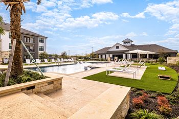 a swimming pool with lounge chairs and a building in the background at The Parker Austin, Pflugerville, TX, 78660