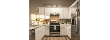 A kitchen with white cabinets and a stainless steel refrigerator.