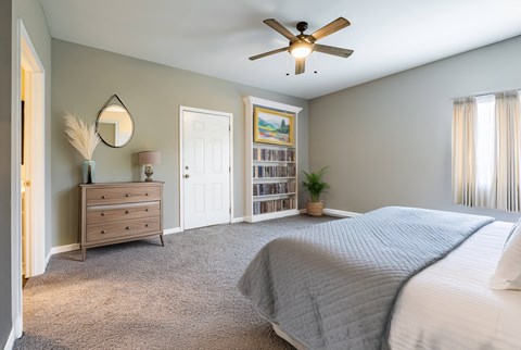 A bedroom with a large bed and a ceiling fan.