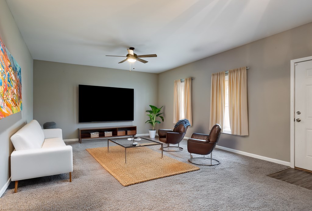 A living room with a white sofa, a coffee table, and a television at Club Villas Apartments, Georgia