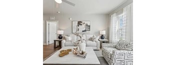 A living room with a white couch, a white coffee table, and a white rug.