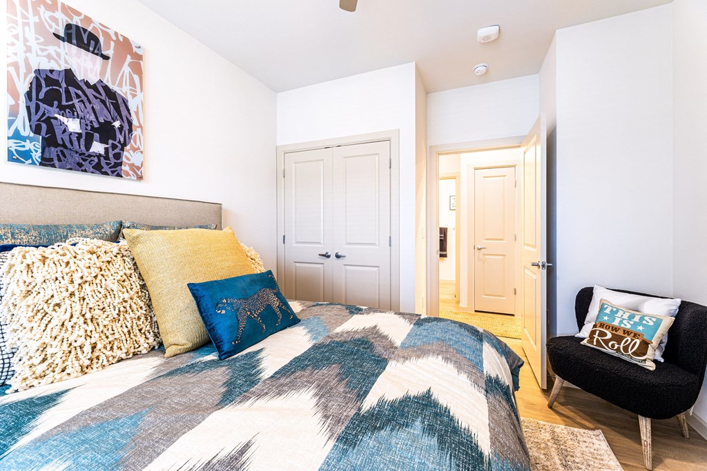 a bedroom with a bed and a chair and a door to a bathroom at The Parker Austin, Pflugerville, Texas
