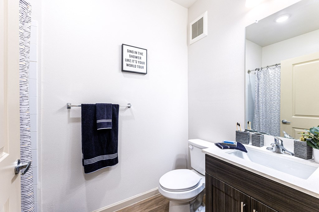 Bathroom with a toilet sink and shower and a mirror at The Parker Austin, Pflugerville, TX