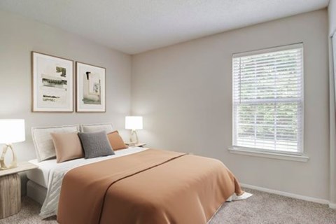 A bedroom with a bed covered in an orange sheet and two framed pictures on the wall.