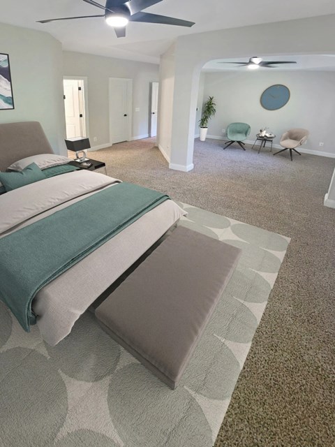 A bedroom with a large bed and a ceiling fan.
