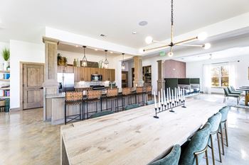 a long communal table in a large kitchen with a bar and a living room at The Parker Austin, Pflugerville