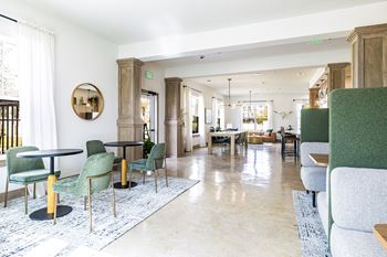 a living room with green chairs and tables and a dining room at The Parker Austin, Pflugerville, Texas