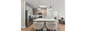 A modern kitchen with a white island and two chairs.