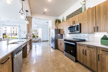 a large kitchen with wooden cabinets and stainless steel appliances at The Parker Austin, Pflugerville