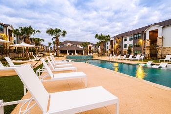 an outdoor pool with lounge chairs and buildings in the background at The Parker Austin, Pflugerville, Texas