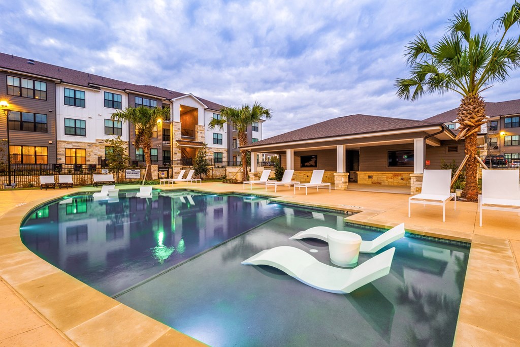 a swimming pool with chairs and a building in the background at The Parker Austin, Pflugerville, 78660