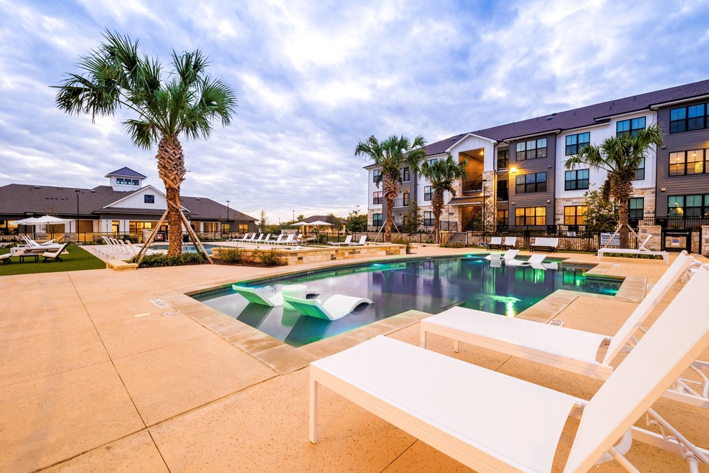 a swimming pool with two white chairs and a building in the background at The Parker Austin, Texas