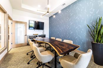 a conference room with a table and chairs and a tv on the wallat The Parker Austin, Pflugerville, Texas