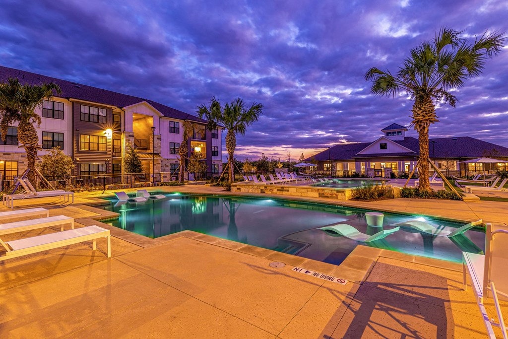 a swimming pool with palm trees at night at The Parker Austin, Pflugerville, Texas