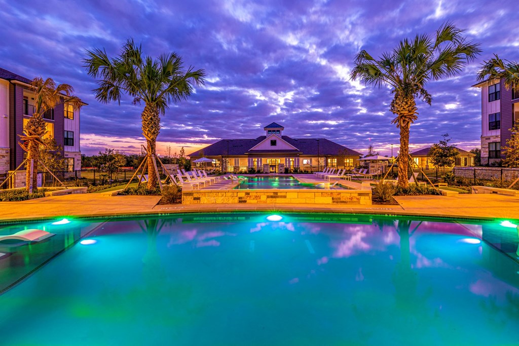 Swimming pool with palm trees and a building in the background Swimming pool with palm trees and a building in the background at The Parker Austin, Pflugerville, Texas