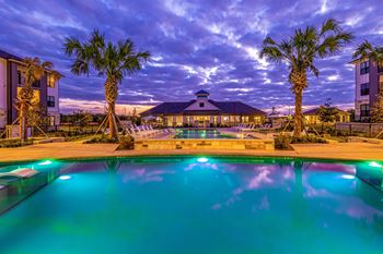 a swimming pool with palm trees and a building in the background at The Parker Austin, Pflugerville, 78660