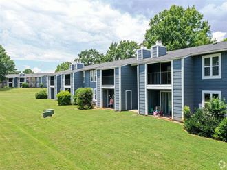 a blue apartment building with a green lawn and trees