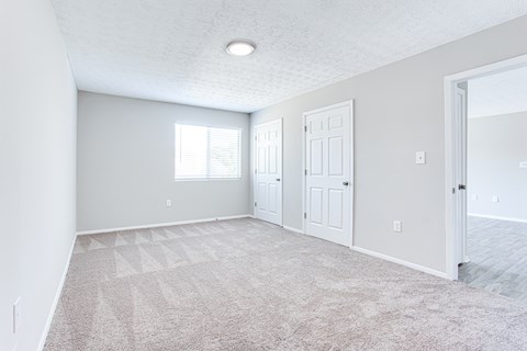 A room with a carpeted floor and a window with blinds.