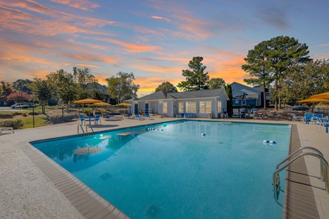 A large swimming pool with a building in the background during sunset.